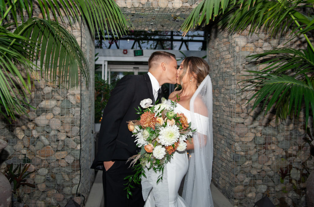 bride and groom kiss during their grand entrance at Planterra Conservatory greenhouse