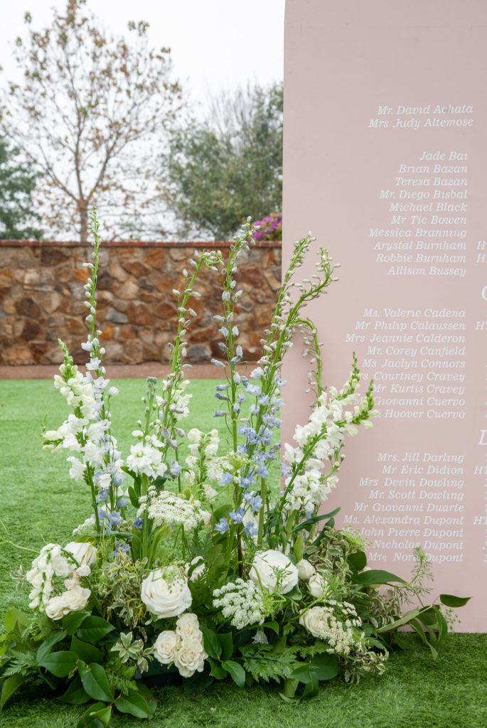 large wedding guest seating chart with a floral arrangement in front on the grand lawn of Bella Collina