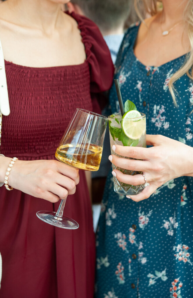 two women wedding guests clicking their wine class and cocktail glass
