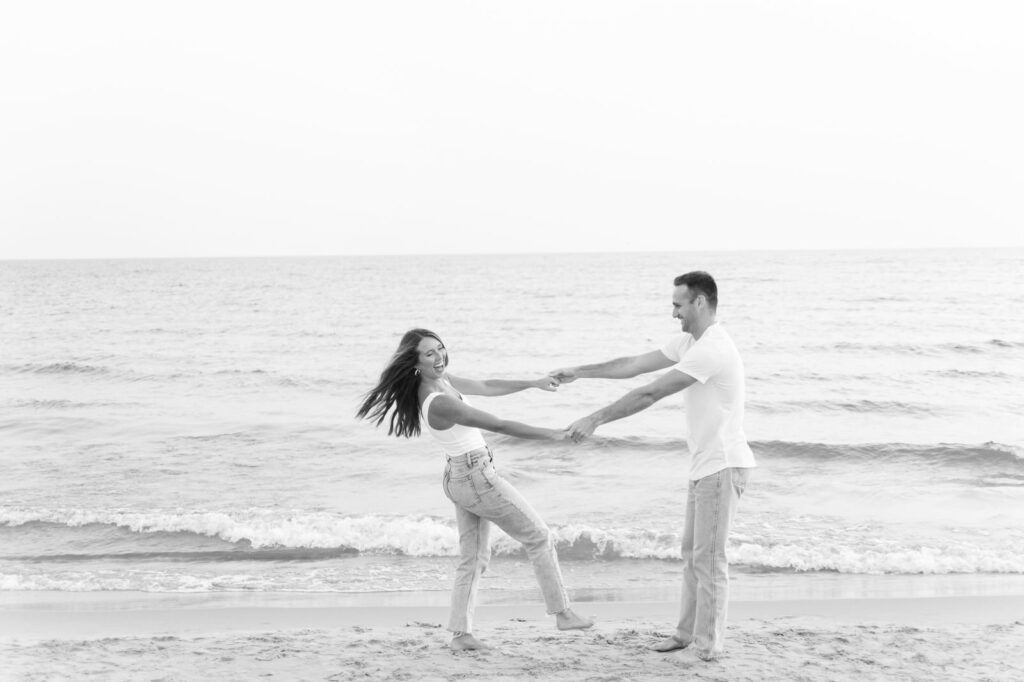 playful couple holding hands and laughing during their Grand Haven engagement photo session
