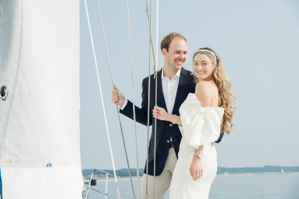 Sunset engagement session on Lake Michigan in wedding attire standing on a sailboat