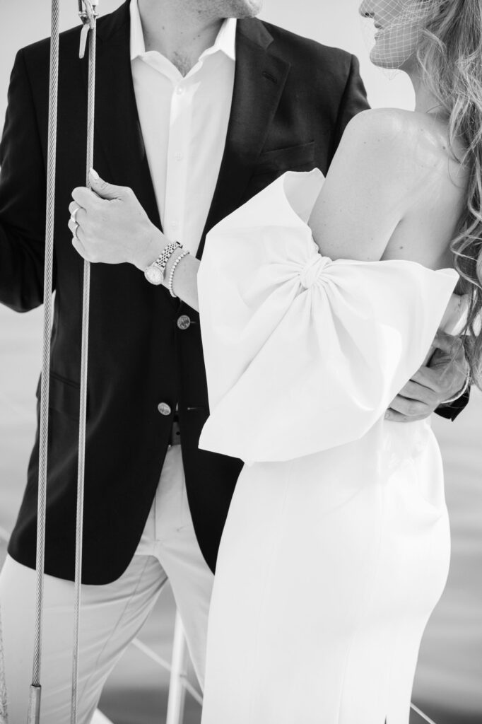 man in a suit hugging a woman with a formal white sleeveless dress with big white bow sleeves