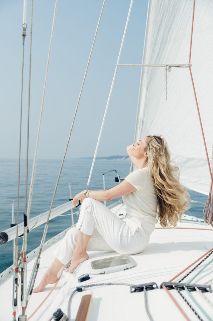 woman sitting on the bow of a sailboat with the lake breeze blowing in her hair