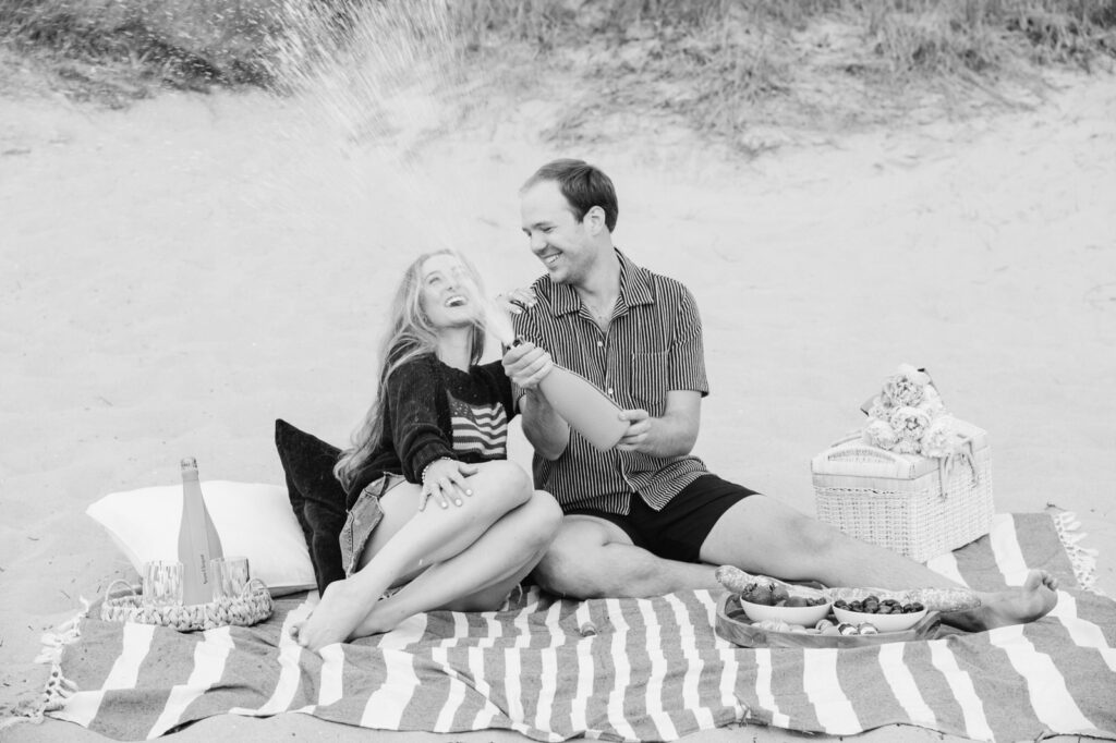 couple popping champagne during their romantic picnic in Saugatuck