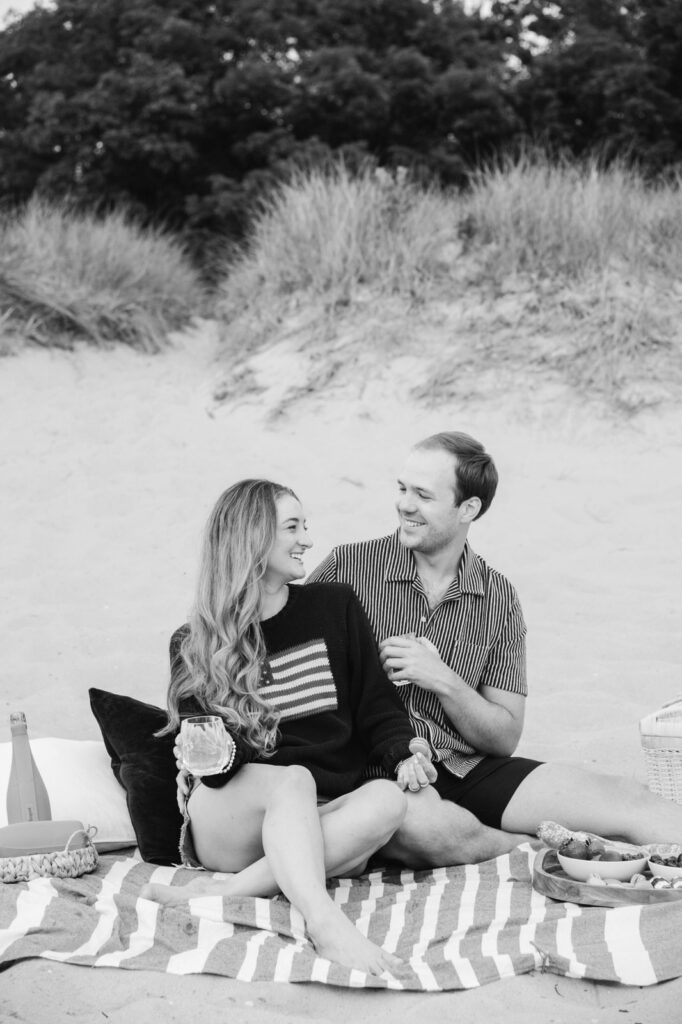 couple enjoying a romantic picnic during their engagement photo session on Lake Michigan