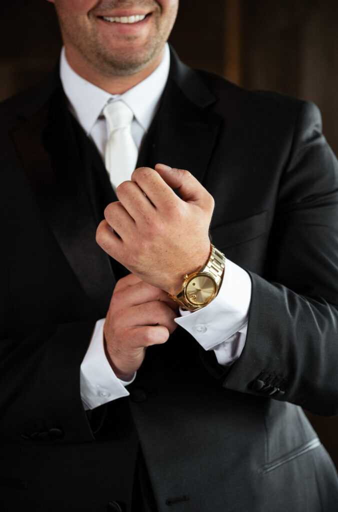 groom adjusting his golden watch on the morning of his wedding day
