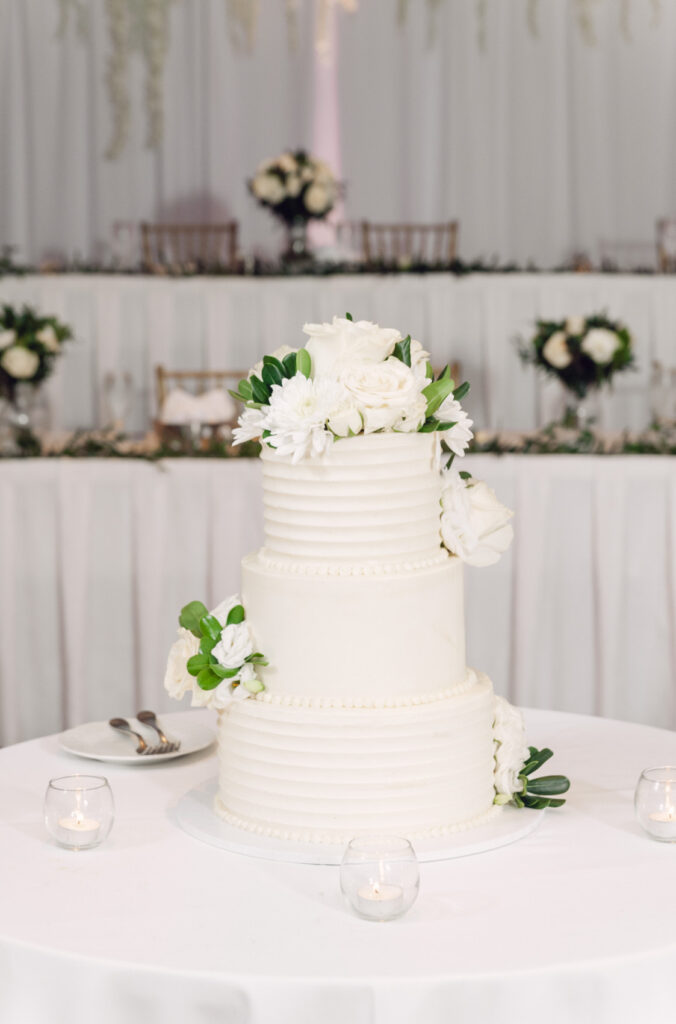 white three tier wedding cake decorated with white and green florals by the Gourmet Cupcake Shoppe in Midland