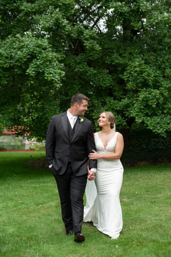 Dow Garden wedding photo of bride and groom walking hand in hand with green trees in the background