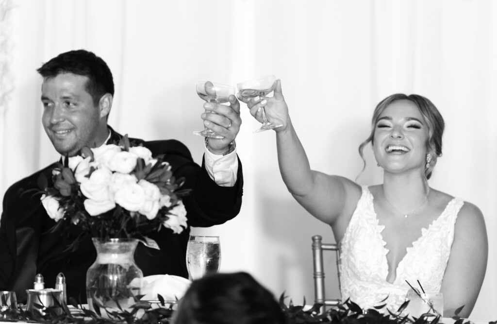 bride and groom raise glasses of champagne during their wedding reception at the H Hotel