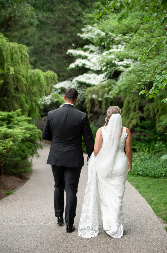 bride and groom walking on a path inside of Dow Gardens on their wedding day