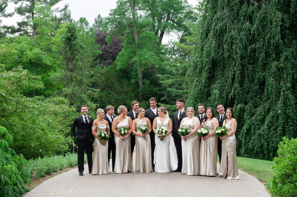 A wedding party of 14 dressed in black suits and satin champagne dresses in Dow Gardens