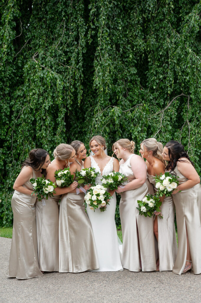 bride surrounded by her bridesmaids dressed in satin champagne colored dresses