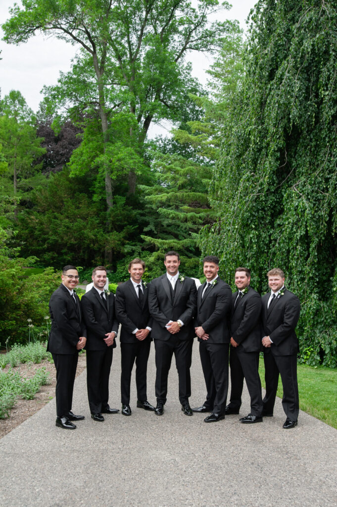 groom surrounded by his groomsmen during bridal party photos at Dow Gardens