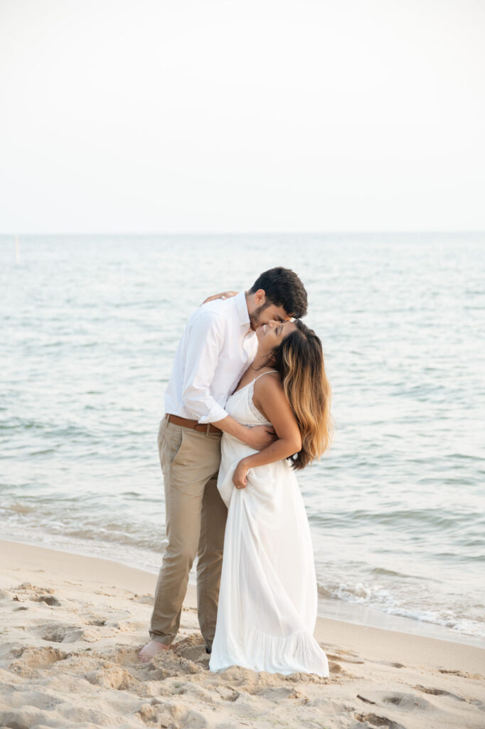 woman smiling towards the sky as her fiance kisses her cheek during their Lake Michigan engagement photos in Grand Haven
