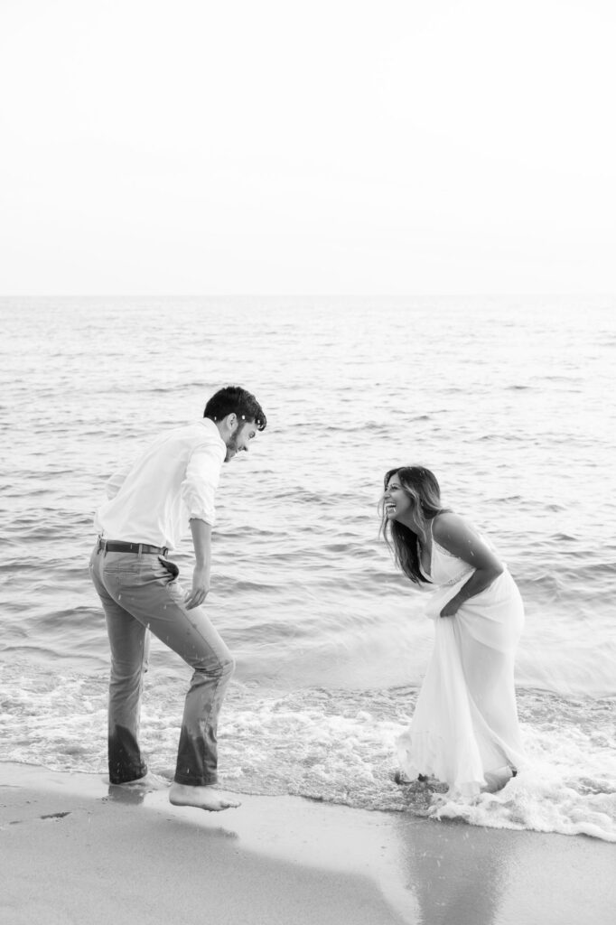 man and woman playing in the water of Lake Michigan during their Olive Shores engagement photo session