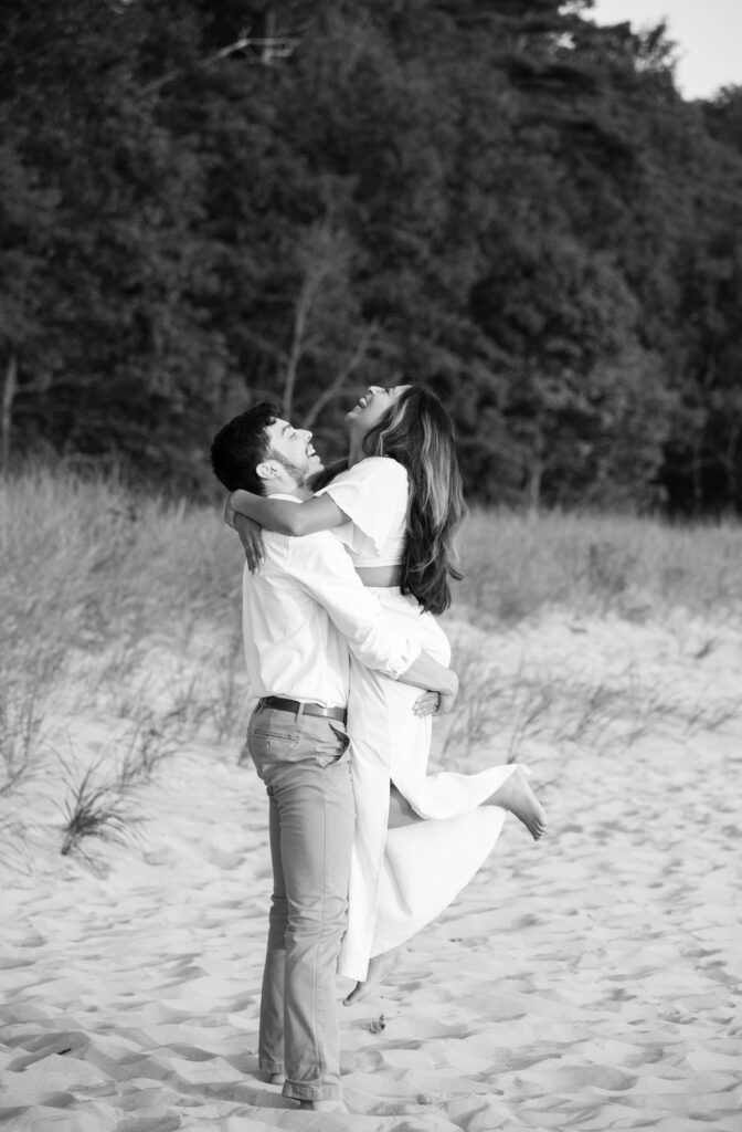 man holding his girl as they both smiles during their engagement photo session on Olive Shores