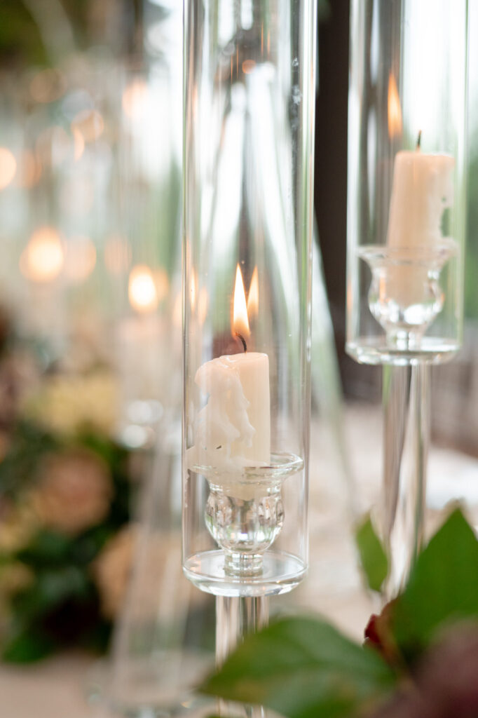 tapered candle glowing inside a thin raised hurricane glass