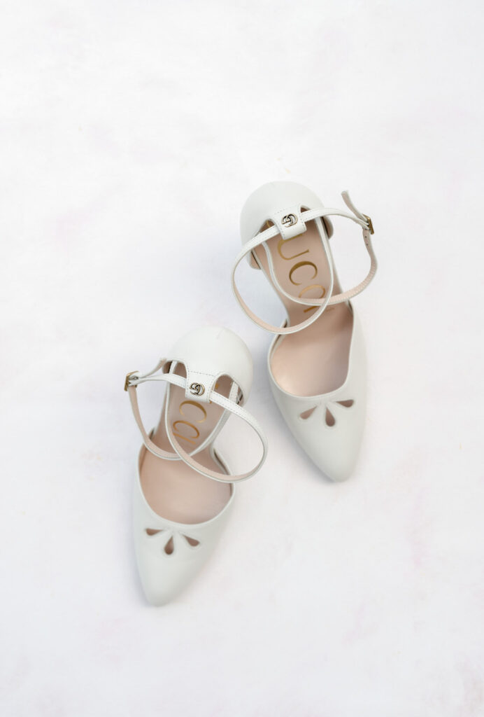 Gucci white heels on a light pink and white styling surface mat