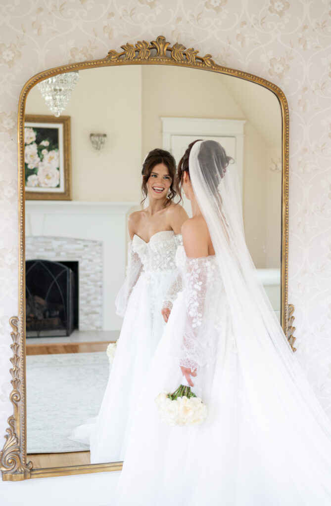 bride smiling at her reflection in a large golden Gleaming Primrose Mirror