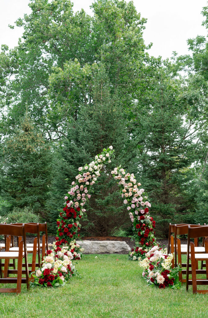 a floral wedding arbor full of pink, red, and white roses