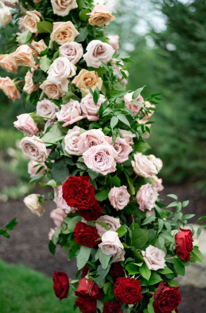 red, white, pink and orange roses on a wedding ceremony arbor