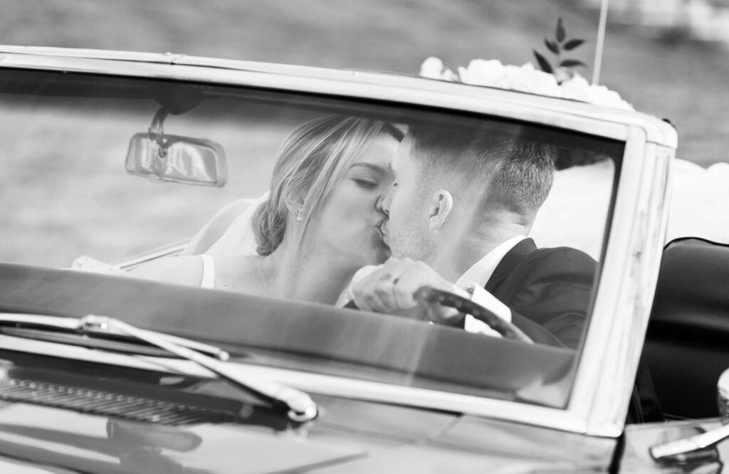 bride and groom kiss sitting inside a vintage Chevrolet Camaro at their spring Waldenwoods Wedding