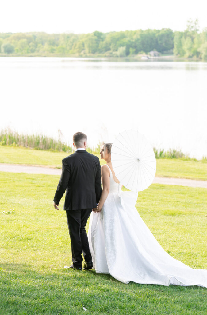 bride and groom walk hand in hand along the water after their Waldenwoods wedding ceremony 