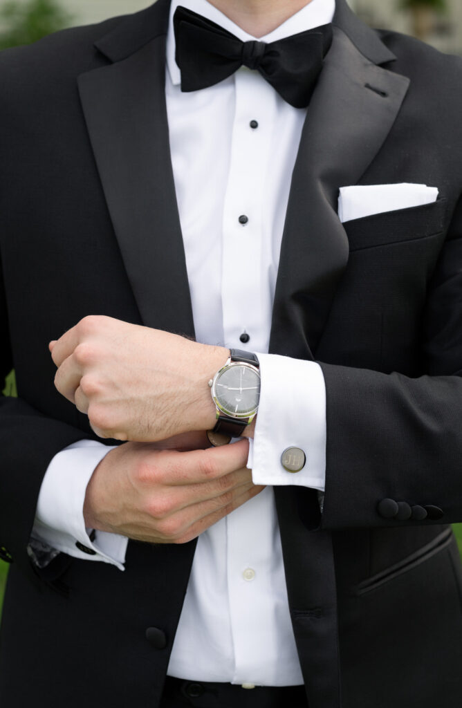 groom adjusting his watch in his classic black tux and custom custom links