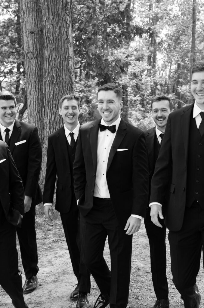 groom smiling and walking with his groomsmen