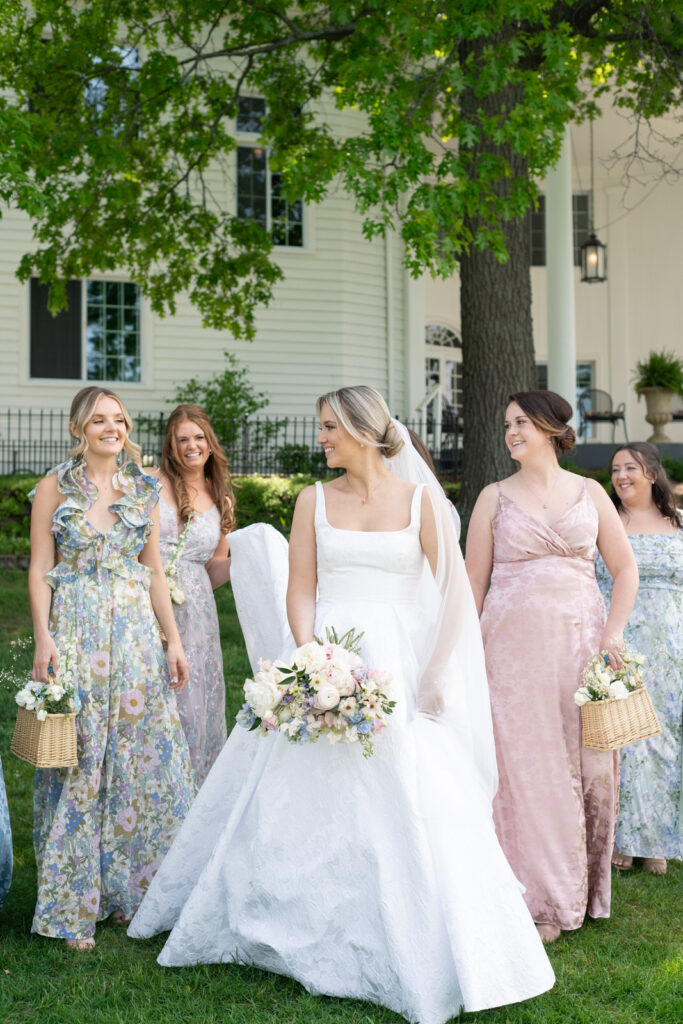 classic bride walking and smiling with her bridesmaids during her spring wedding at Waldenwoods in Howell, MI
