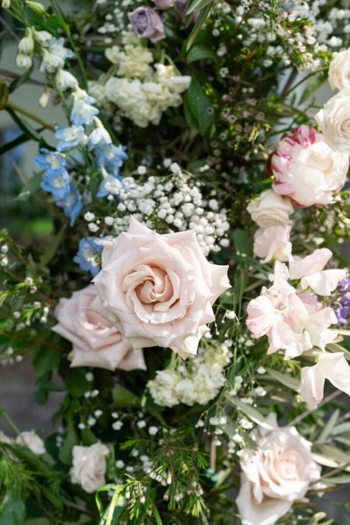 detail of floral wedding arbor with light pink roses and other pastel flowers