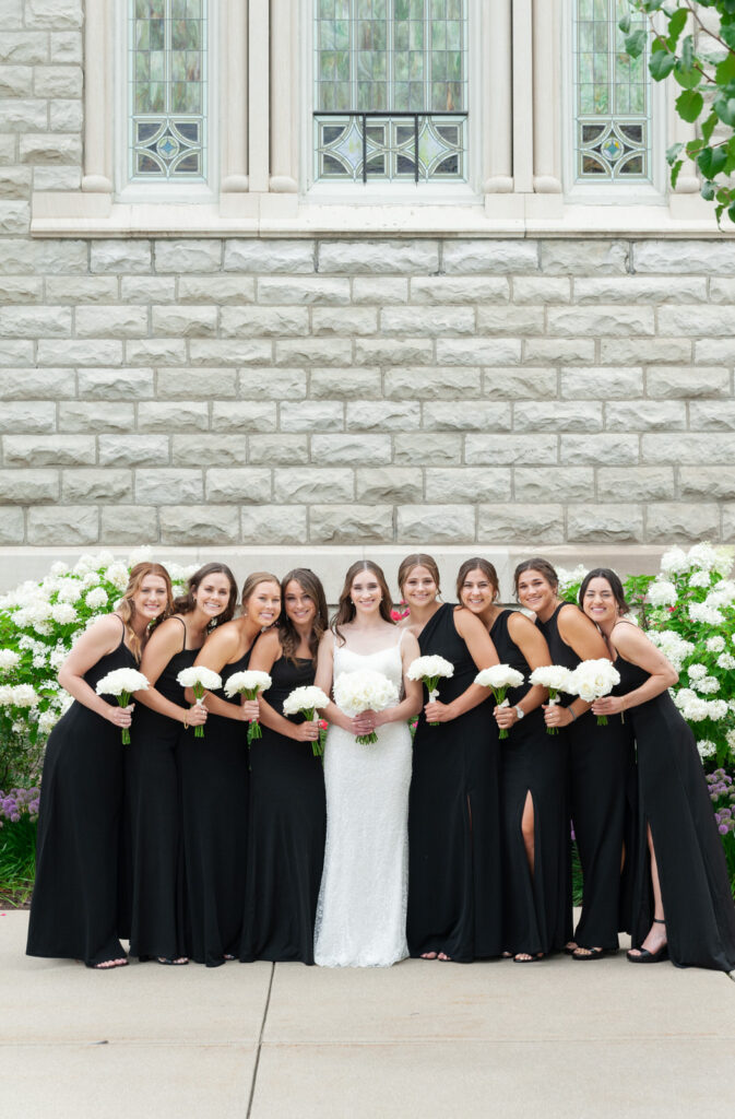 bride with her bridesmaids in black dresses in front of Basilica of St. Adalbert in downtown Grand Rapids