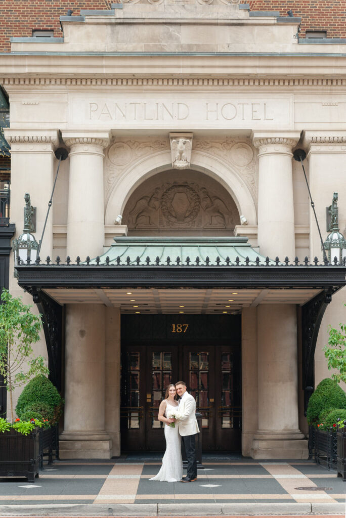 bride and groom smiling in front of the Amway Grand Plaza Hotel in downtown Grand Rapids