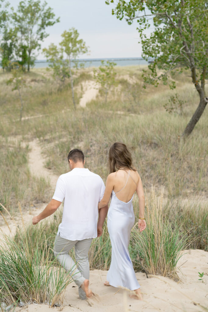 man leading his woman down the sand dunes on Lake Michigan in Muskegon