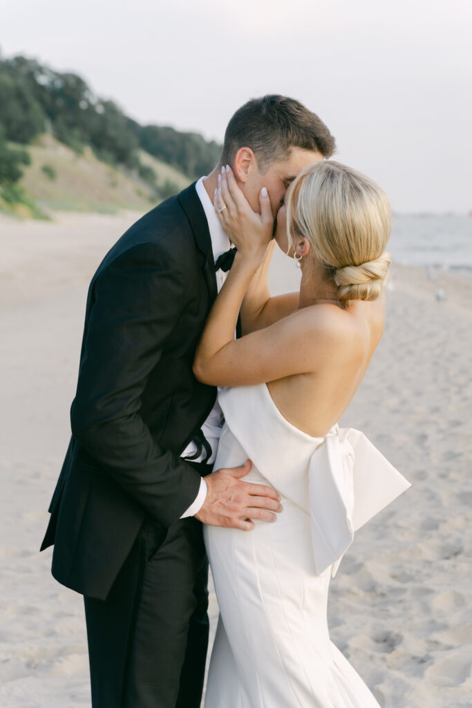 bride kissing her husband at sunset on Lake Michigan
