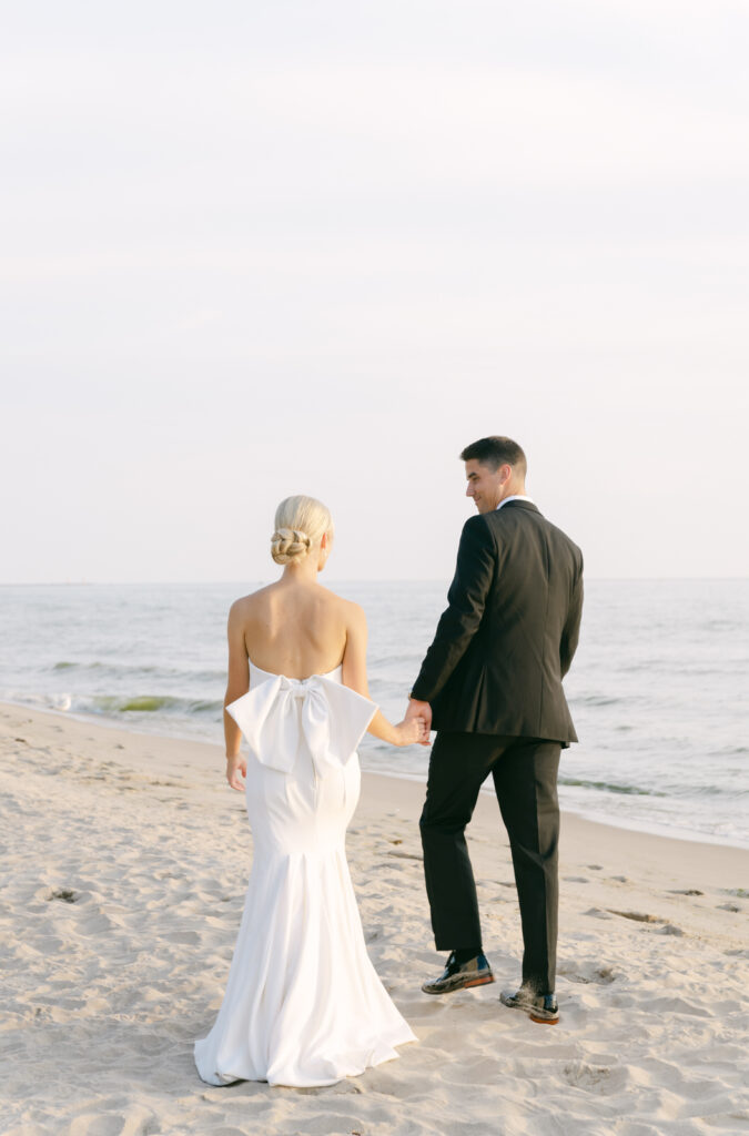 bride and groom walking in the sand with Lake Michigan in the background at sunset