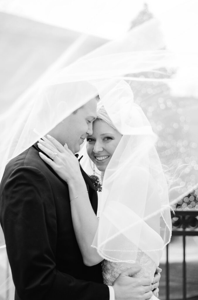 bride and groom snuggle under the veil outside of Saint John's Resort on their winter wedding day