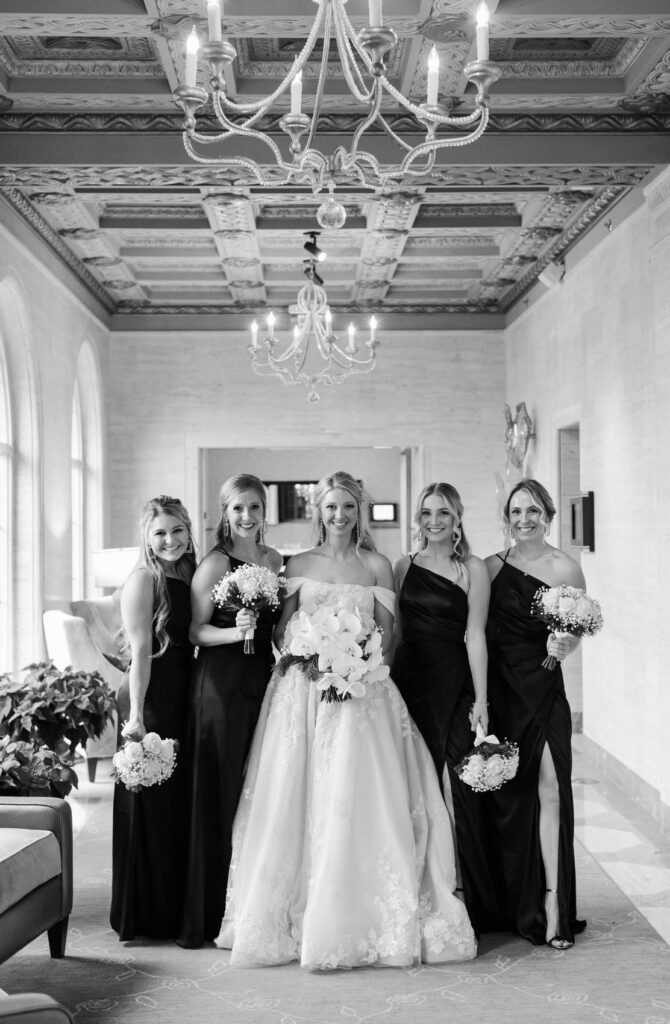 bride with her bridesmaids in black dresses in the hallway of Saint John's Resort in Plymouth