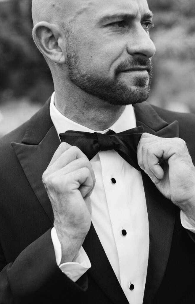 groom adjusting his bow tie on his summer wedding day at Bay Pointe Inn