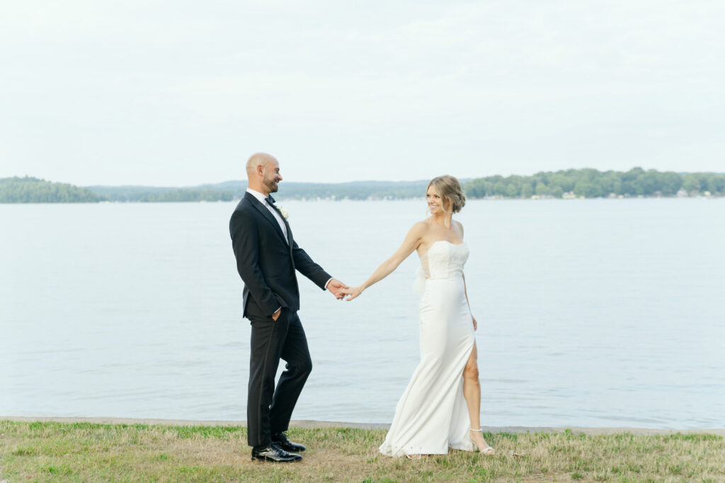 Bride and Groom walking hand in hand along the shore of Gun Lake in Shelbyville, Michigan