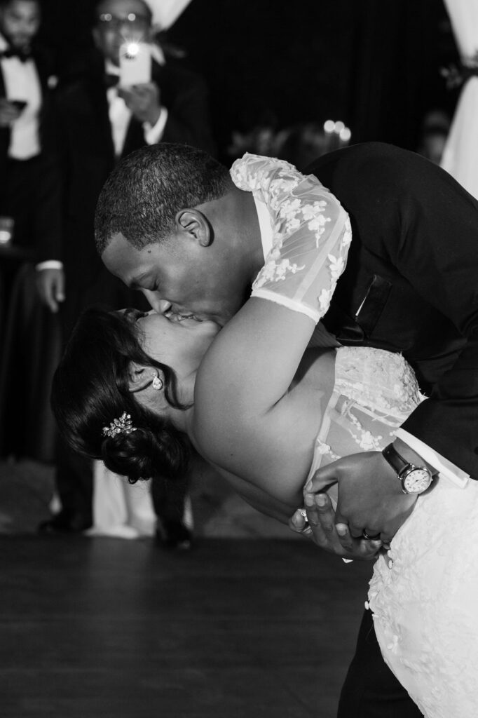 groom dips his bride over and kisses her during their first dance at Planterra Conservatory