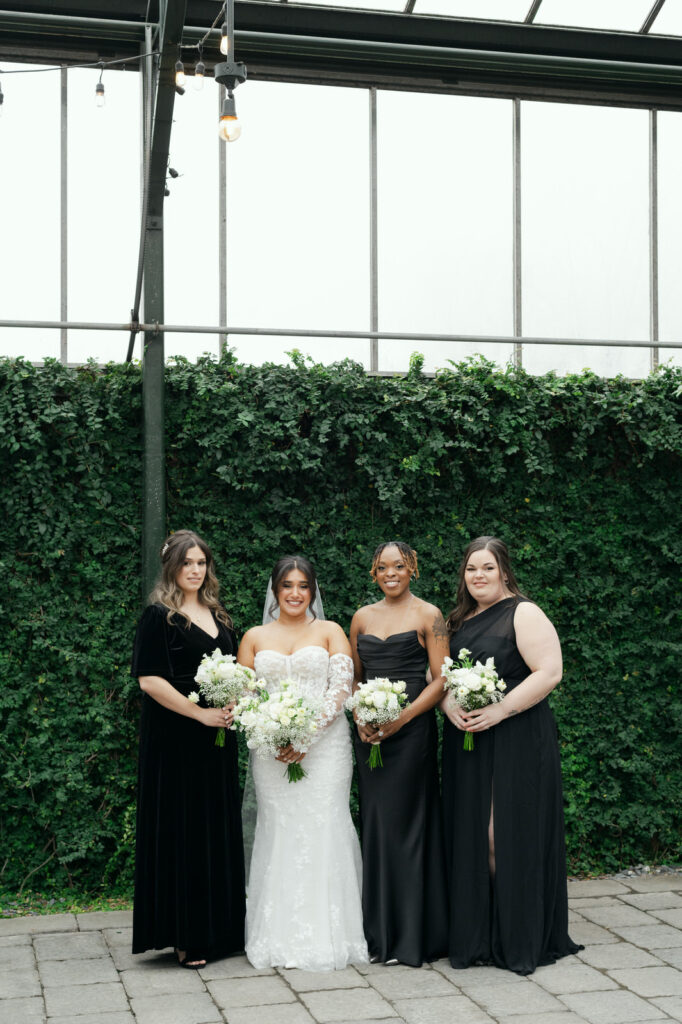 bride standing next to her three bridesmaids in long black dresses