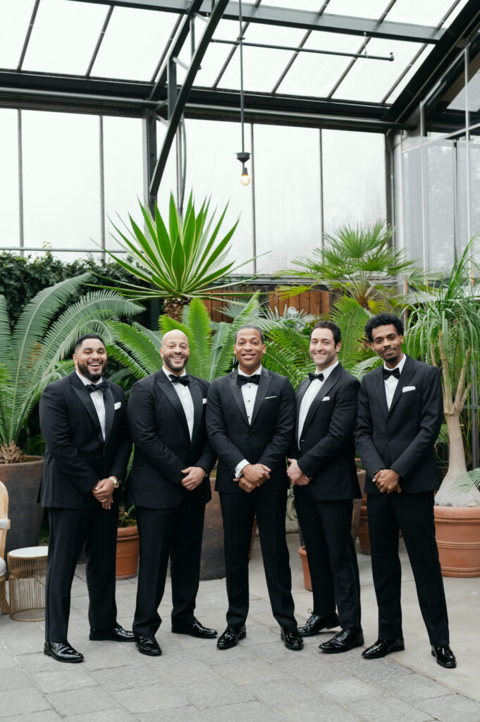 groom with his four groomsmen all in black tuxedos at Planterra