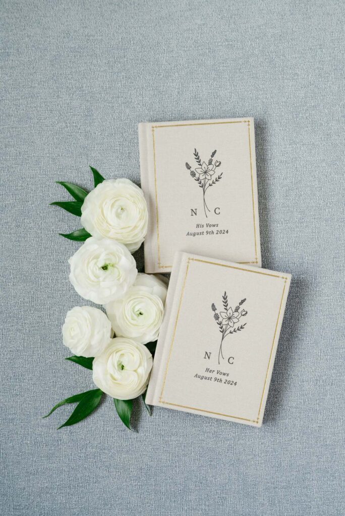 2 vow books with white flowers resting along the books