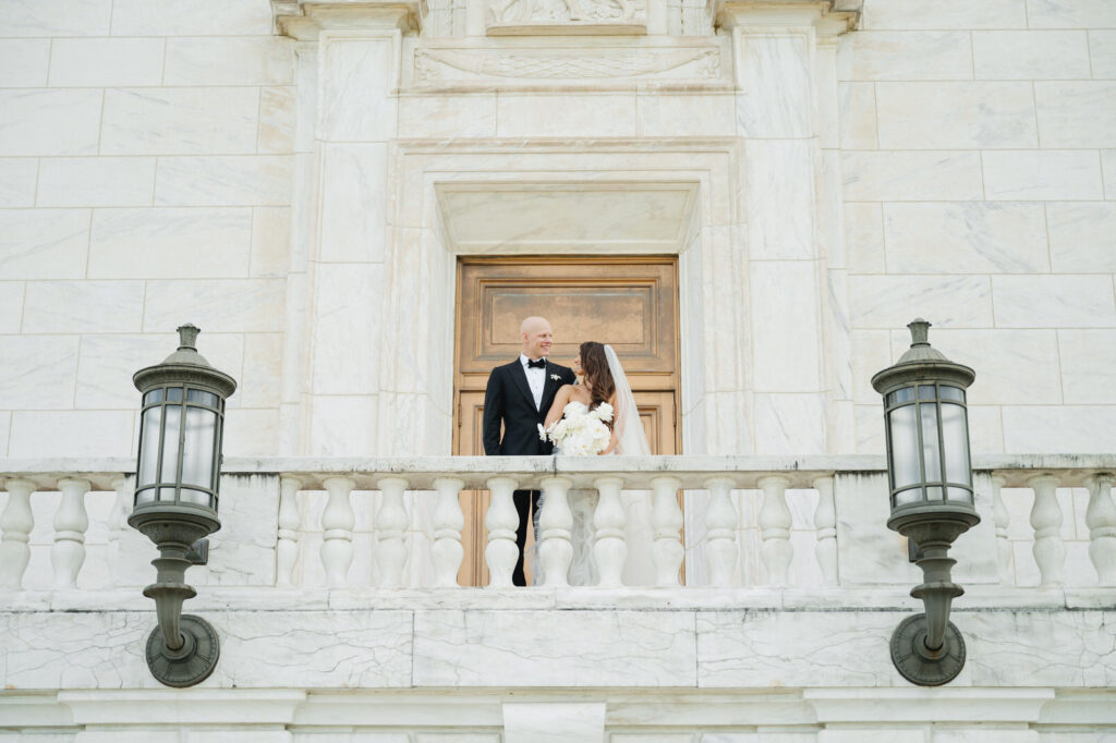 bride and groom smile at each other on top of the marble balcony of the Detroit Institute of Arts