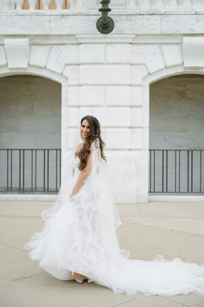 bride twirling her Ines Di Santo wedding gown in front of the white marble of the Detroit Institute of Arts