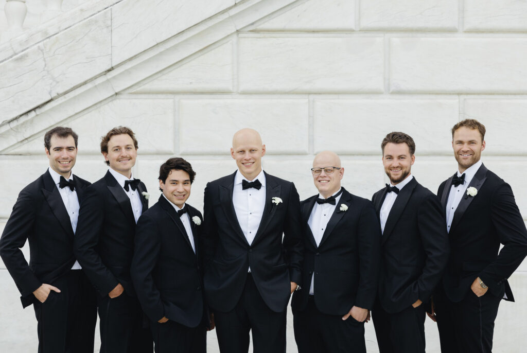 groom and his six groomsmen all in black suits smiling at the Detroit Institute of Arts