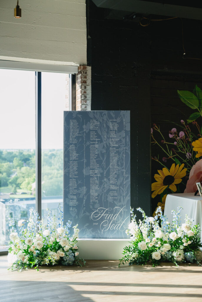 blue and white seating chart surrounded by blue and white floral arrangements on the 9th floor of Chroma Detroit