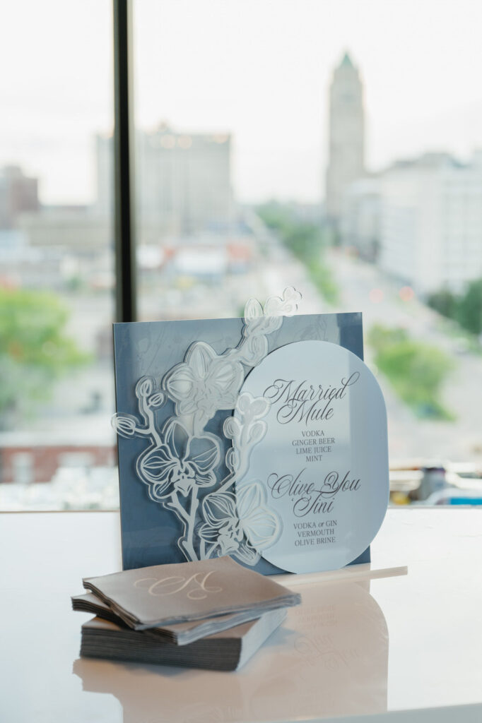 blue acrylic bar sign featuring the drinks "married mule" and "Olive You Tini" with the Detroit skyline in the background