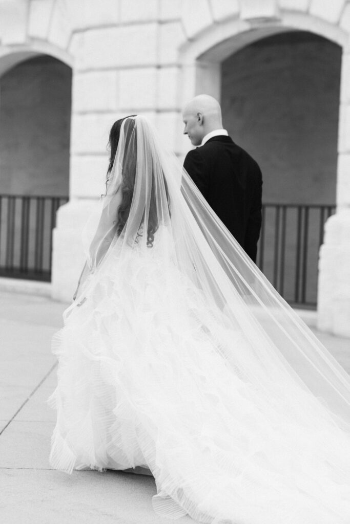 bride and groom walk holding hands in front of the Detroit Institute of Arts